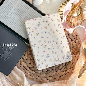 Könnte beinhalten: Ein weißer Kindle E-Reader mit einem Blumenmuster und dem Text "Irislife Kindle" auf dem Cover. Der Kindle liegt auf einer geflochtenen Weidenoberfläche.