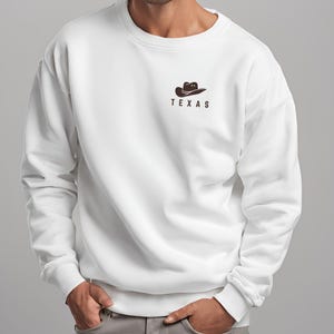 May include: White sweatshirt with a brown cowboy hat graphic and the word "TEXAS" printed below it.