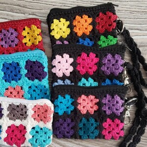 May include: Three crocheted zipper pouches with colorful square patterns. The pouches are black, red, and white with a variety of colors in the squares. The pouches have black zipper pulls and are attached to a black crocheted strap.