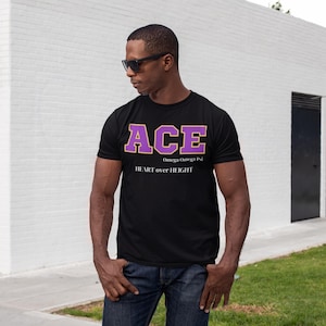 Puede incluir: Camiseta negra con un gráfico "ACE" morado y dorado y el texto "Omega Omega Psi" y "HEART over HEIGHT".