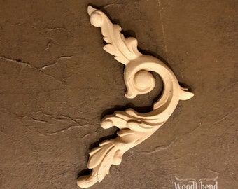 May include: A light-colored, unfinished wooden decorative scroll with a swirling design. The scroll features a central circular element and leaf-like details. The WoodUbend logo is visible in the bottom right corner.