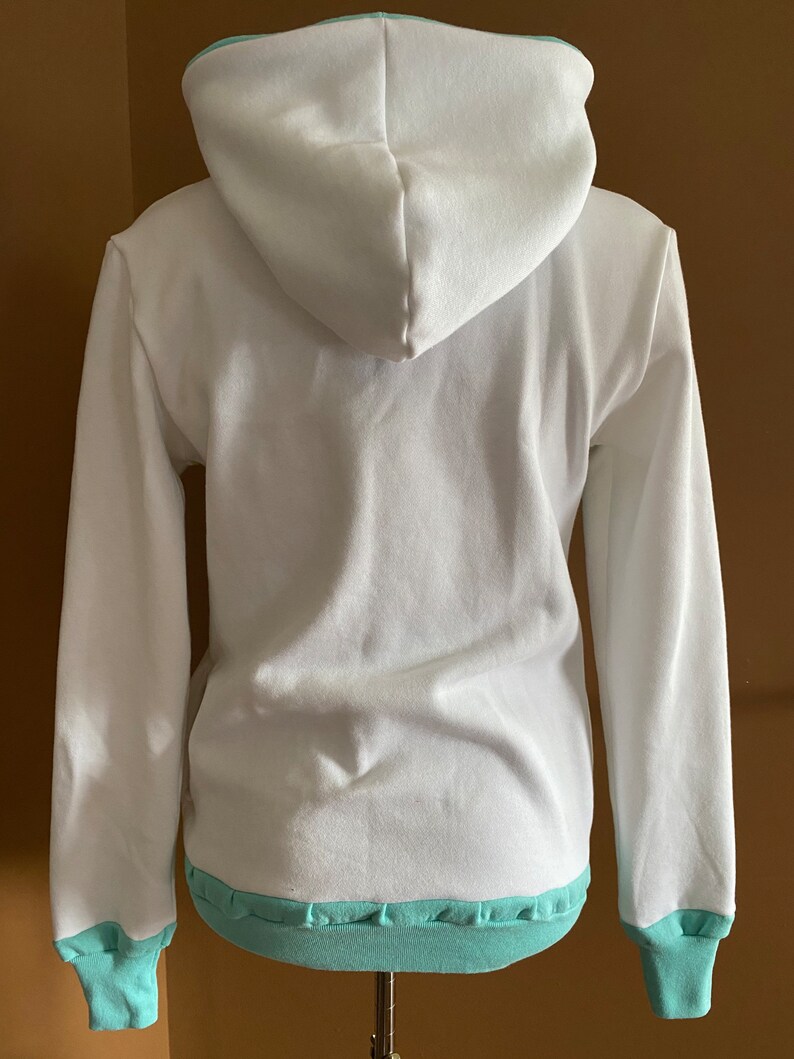 May include: White hooded sweatshirt with a light blue trim around the hood, cuffs, and hem.