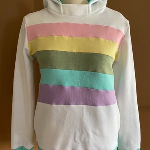 May include: White hooded sweatshirt with a multi-colored striped pattern. The stripes are pink, yellow, green, light blue, and purple.