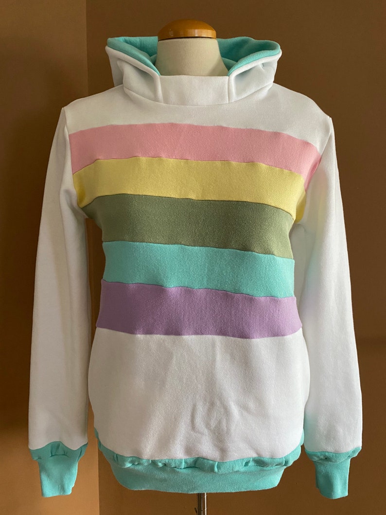 May include: White hooded sweatshirt with a multi-colored striped pattern. The stripes are pink, yellow, green, light blue, and purple.