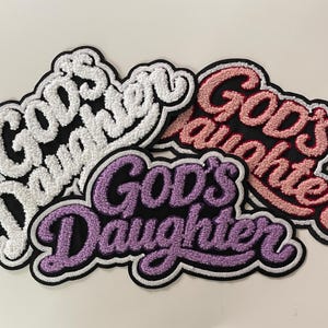 May include: Embroidered patches in white, pink, and purple, each with the words "God's Daughter" in a script font. The patches have a black background and a white border. The patches are a religious theme.