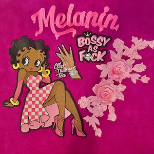 May include: A collection of embroidered patches including a cartoon character in a pink and white checkered dress, a hand gesture patch with the text Clock That Tea, a patch reading Bossy As Fck, the word Melanin, and a pink floral lace applique.