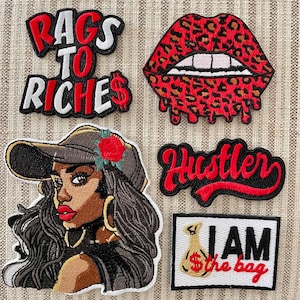 May include: Five embroidered iron-on patches with a red, white, and black color scheme. The patches feature a woman with a baseball cap, a red mouth with leopard print, the words "Rags to Riches", the word "Hustler", and the words "I am the bag" with a money bag.