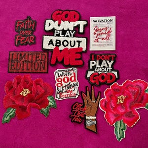 May include: A collection of embroidered patches featuring various designs including red and white text reading "Faith Over Fear," "God Don't Play About Me," "Limited Edition," "I Don't Play About God," "With God All Things Are Possible," and "Clock That Tea," alongside two red flower patches and a white rectangular patch with the text "Salvation Jesus Paid It All."