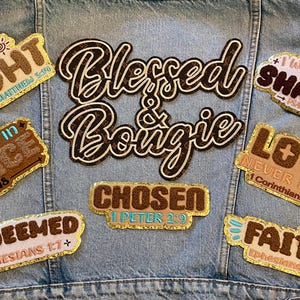 May include: A collection of embroidered patches with inspirational phrases and Bible verses, including "Be the Light," "Blessed & Bougie," and "Love Never Fails." The patches are in various colors and fonts, with gold trim, and are affixed to a denim jacket.