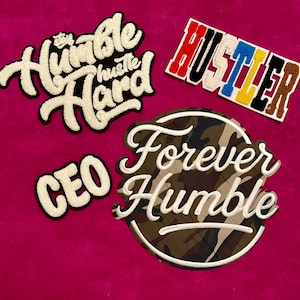 May include: Four embroidered patches featuring text designs. One patch reads "Stay Humble Hustle Hard" in white script, another says "HUSTLER" in multi-colored block letters, a small patch reads "CEO" in white, and a circular patch says "Forever Humble" over camouflage.