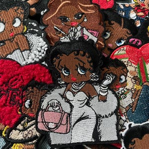 May include: Embroidered patches featuring a cartoon woman in various poses and outfits. The patches showcase a woman with dark skin, large eyes, and red lips. Some patches include a pink purse, a white fur coat, and other accessories. The patches are in various colors.