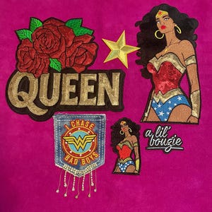 May include: A collection of embroidered patches featuring a large red rose cluster above the gold sequined text QUEEN, a gold star, a large Wonder Woman figure, a denim pocket patch with the text I CHASE BAD BOYS, a small Wonder Woman, and a lil' bougie text.