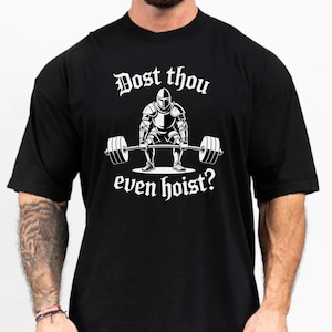 Op de afbeelding: Zwart t-shirt met een witte afbeelding van een ridder die een halter optilt. De tekst "Dost thou even hoist?" staat boven en onder de illustratie van de ridder. Het t-shirt heeft een ronde hals en korte mouwen.