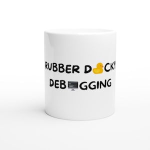 Può includere: Tazza in ceramica bianca con testo nero che recita "Rubber ducky debugging" e un'icona di papera di gomma gialla.