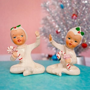 Könnte beinhalten: Eine weiße Keramik-Tasse mit schwarzem Henkel und dem Text "But First, Coffee" in fetter, schwarzer Schrift. Die Tasse steht vor einem neutralen Hintergrund, der ihr schlichtes Design hervorhebt.