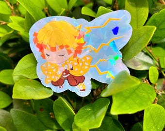 May include: A holographic sticker featuring a cartoon character with yellow hair, a yellow and brown patterned shirt, and a lightning bolt design. The sticker is on a green leafy background.