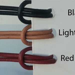 May include: Three leather cords in black, light brown, and red brown colors. The cords are tied in a knot and are displayed on a white background with the color names written next to them.