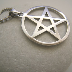 May include: A silver pendant necklace featuring a pentagram, or five-pointed star, in a circle. The pendant is made of stainless steel and has a polished finish.