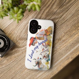 May include: White phone case featuring a watercolor illustration with the text "I lost my heart in Vrindavan." The artwork depicts a figure with a red head covering and several animals in shades of yellow, orange, and blue.