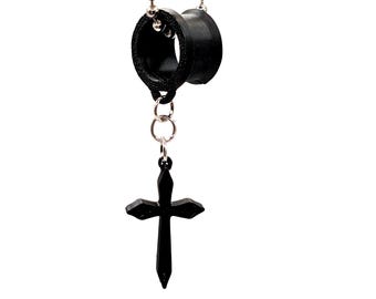 May include: A black cross pendant hangs from a silver ball chain, connected to a pair of black, circular ear gauges. The gauges are connected by a small silver chain. The jewellery is set against a white background.
