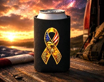 May include: Black can cooler with a gold ribbon design incorporating the American flag and an eagle. The ribbon features red, white, and blue stripes and stars. The cooler sits on a wooden surface, with an American flag visible in the background.
