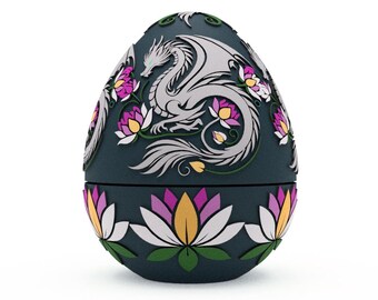 Può includere: Una scatola decorativa a forma di uovo di colore blu scuro con un design di drago bianco e fiori rosa. La scatola è chiusa e ha un motivo floreale sul fondo.