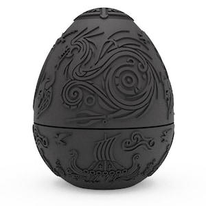 May include: A black egg-shaped object with intricate carvings of dragons and other mythical creatures. The egg is made of a smooth, matt material.
