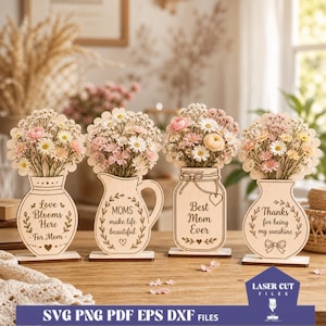 Op de afbeelding: Vier houten bloemenvaasdecoraties met bloemstukken. Elke vaas heeft een unieke vorm en boodschap: "Love Blooms Here - For Mom", "Moms make life beautiful", "Best Mom Ever" en "Thanks for being my sunshine".