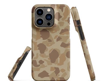 May include: A smartphone case featuring a tan, beige, and brown camouflage pattern. The case is shown from three angles: a full back view with a triple-lens camera cutout, a side view showing button cutouts, and a bottom view with speaker ports.
