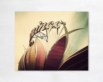 May include: A vintage-style photograph of the iconic "mingo" sign, a large, illuminated sign with a stylized flower design. The sign is made of metal and has a red, white, and yellow color scheme. The sign is lit up with white lights, creating a bright and eye-catching display.