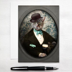 Puede incluir: Un gato atigrado con un sombrero bomb&iacute;n negro y una pajarita turquesa, vestido con un traje oscuro, sosteniendo un vaso de cerveza Guinness. El gato est&aacute; posado sobre un fondo vintage, adornado y con patrones.