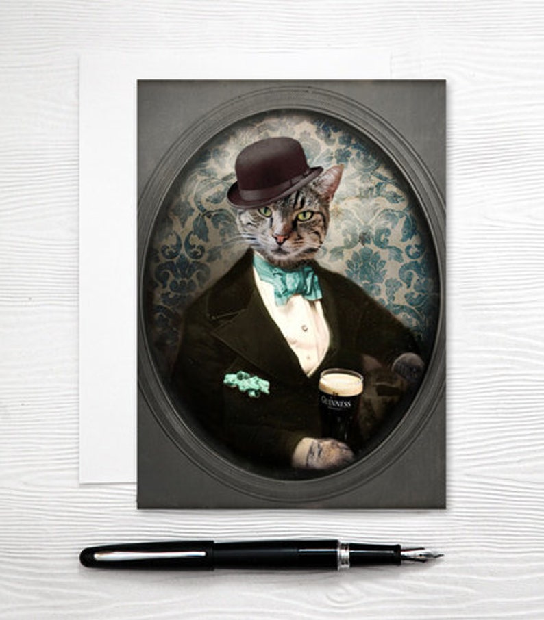 Puede incluir: Un gato atigrado con un sombrero bomb&iacute;n negro y una pajarita turquesa, vestido con un traje oscuro, sosteniendo un vaso de cerveza Guinness. El gato est&aacute; posado sobre un fondo vintage, adornado y con patrones.