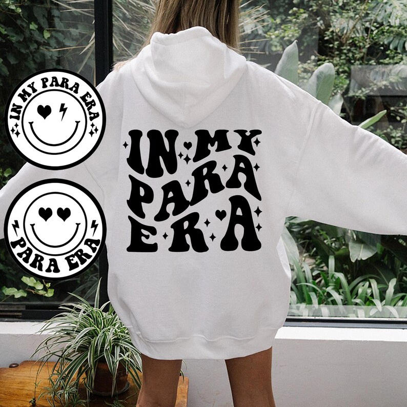May include: White hoodie with a black graphic print that says "In My Para Era" with a smiley face and hearts.