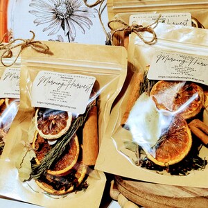 May include: Several clear plastic pouches filled with dried orange slices, cinnamon sticks, and herbs. Each pouch has a brown paper label with the text "Morning Harvest" and the Etsy shop URL. The pouches are tied with twine.