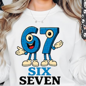 Puede incluir: Sudadera blanca con un gráfico de dibujos animados de los números 67 en azul con ojos, brazos y piernas. Las palabras "SIX SEVEN" están impresas en azul y negro debajo. El diseño está centrado en la parte delantera.