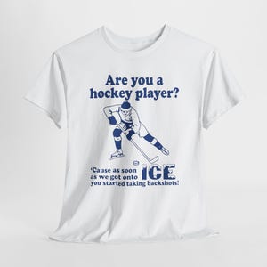 May include: White t-shirt with a navy blue graphic of a hockey player and the text "Are you a hockey player?" and "Cause as soon as we got onto ice you started taking backshots!"