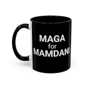 May include: Black and white ceramic mug with the text "MAGA for MAMDANI" in white block letters. The mug has a black handle and interior, with a white stripe on the exterior.