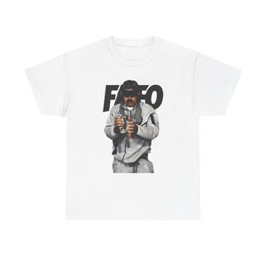 May include: White t-shirt featuring a graphic of a person wearing sunglasses and a gray sweatsuit, holding a water bottle and a hot dog. The word "FAFO" is printed in bold black letters above the person.