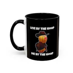May include: Black and white ceramic coffee mug with the text "LIVE BY THE GOOP DIE BY THE GOOP". The mug features a cartoon character wearing a cowboy hat and a brown jacket.