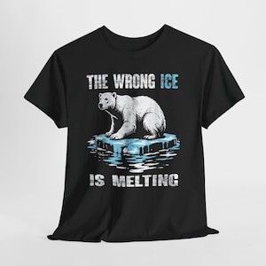 Puede incluir: Camiseta negra con un oso polar sobre un témpano de hielo derritiéndose. El texto "THE WRONG ICE IS MELTING" está impreso en azul y blanco, transmitiendo un mensaje medioambiental.