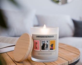 Op de afbeelding: Een brandende, matglazen kaars met een houten deksel staat op een houten tafel. De kaars heeft de tekst "LABRADOR RETRIEVER" en drie ingelijste hondenportretten. De houten deksel ligt ernaast.