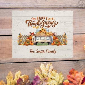 May include: A white wooden sign with a Thanksgiving themed design. The sign features a vintage truck filled with pumpkins and sunflowers. The text "Happy Thanksgiving" is written in brown cursive lettering. The sign is personalised with the text "The Smith Family".