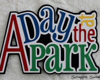 May include: A Day at the Park sign made of colorful foam letters with a black background. The letters are outlined in white. The sign is perfect for a party or event.