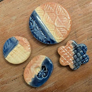 May include: A white ceramic mug with a black handle and the text "But First, Coffee" in a bold, black font. The mug is filled with a dark liquid, likely coffee, and sits on a light-colored surface.