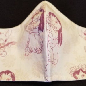 May include: A white face mask with a pink and white print of Lilo and Stitch characters. The mask has elastic ear loops.
