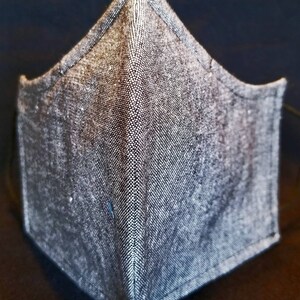 May include: A gray fabric face mask with a pointed shape and a textured surface.