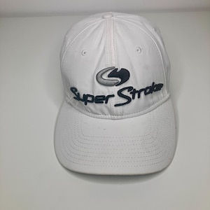 May include: White baseball cap with the text "Super Stroke" in dark blue. The cap has a curved brim and a logo above the text. The cap is made of a lightweight material and has a button on top.