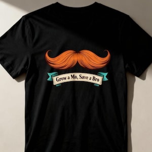 May include: Black t-shirt with a large orange mustache graphic. The text "Grow a Mo, Save a Bro" is displayed on a teal banner beneath the mustache. The shirt is made of a soft material. A fun, novelty item.
