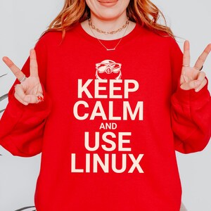 May include: Red sweatshirt with a white graphic that says "Keep Calm and Use Linux" with a cartoon penguin wearing sunglasses.