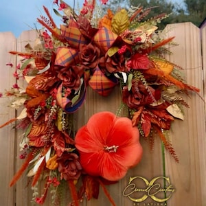 Könnte beinhalten: Ein herbstliches Kranz mit einem großen orangefarbenen Samtkürbis unten. Der Kranz ist mit burgunderfarbenen Rosen, orangefarbenen und gelben Blättern und einem karierten Band geschmückt. Der Text "Curnel Creations by Latisha" ist sichtbar.